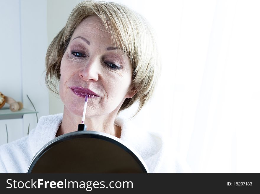 Mature beautiful Woman applying lipstick