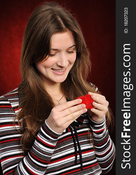 Beautiful woman with a heart gift on the red background