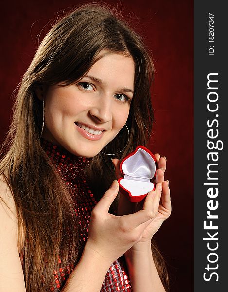 Beautiful woman with a heart gift on the red background