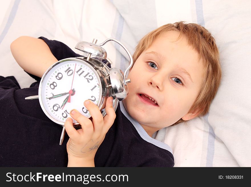 Little boy in bed with a clock