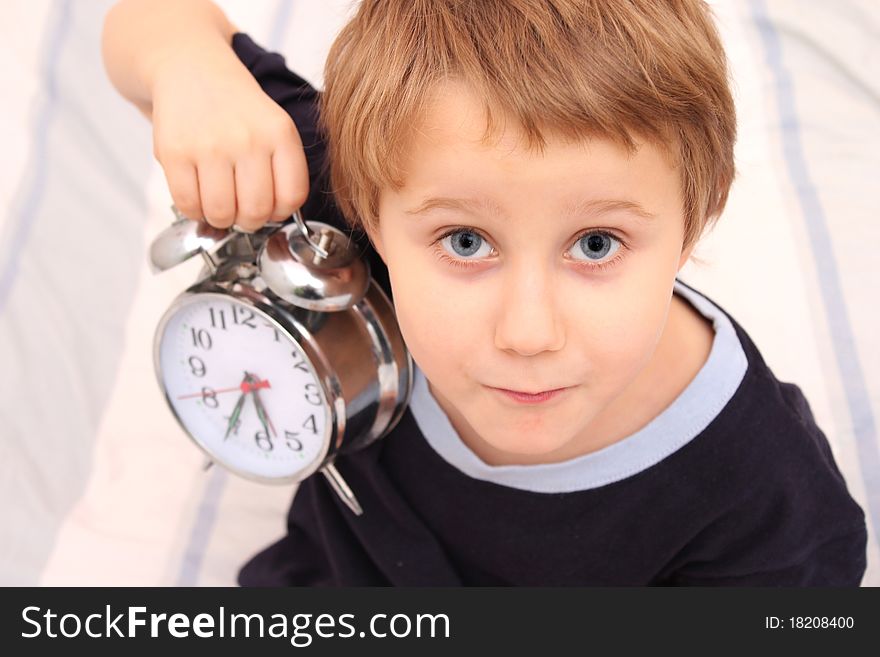 Little boy in bed with a clock