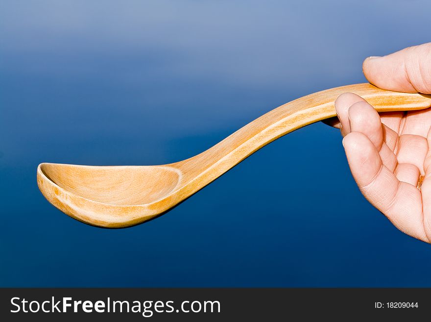 Wooden spoon in hand on a blue background