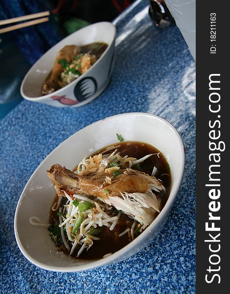 Image of thai soup with chiken on a white plate on a blue table