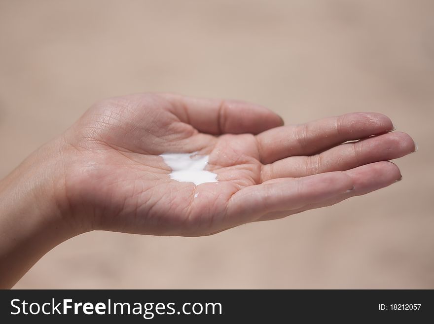 Sunblock on a female hand on the background of the beach. Sunblock on a female hand on the background of the beach