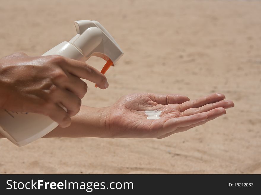 Tanner is applied from the bottle at the woman's hand on the beach. Tanner is applied from the bottle at the woman's hand on the beach
