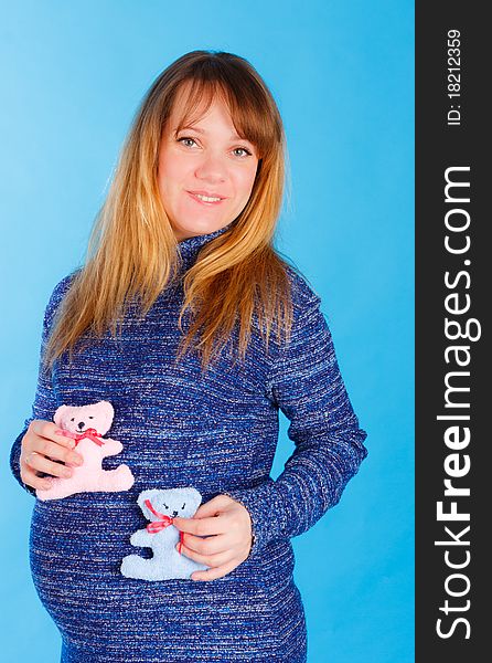 Beautiful pregnant woman with two plush bears in her hands