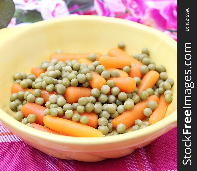 Peas and carrots in a yellow bowl