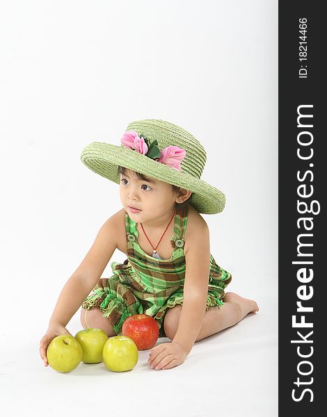 A laughing girl with a green hat is playing some apples. A laughing girl with a green hat is playing some apples.