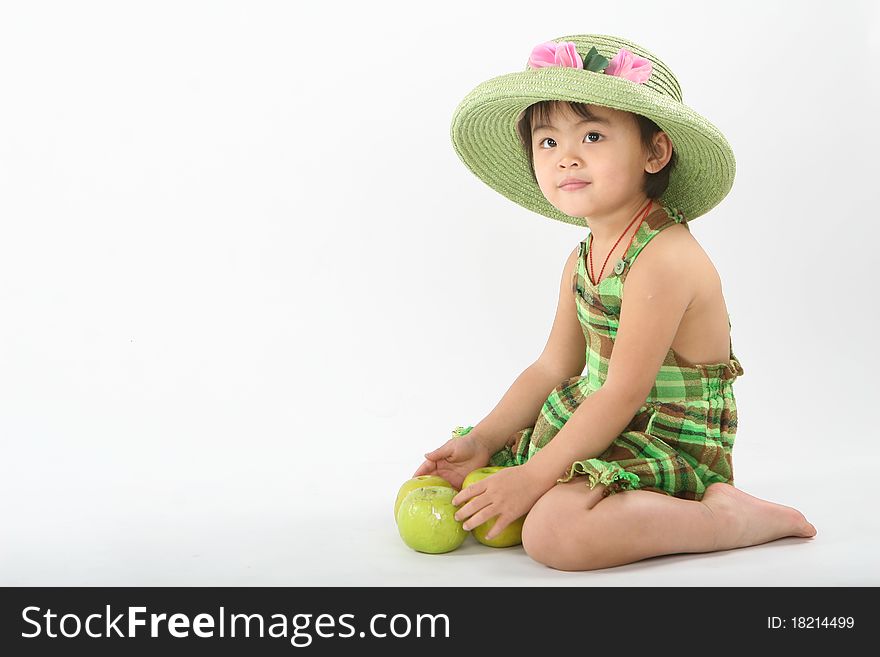 A girl with a green hat is playing some apples. A girl with a green hat is playing some apples.