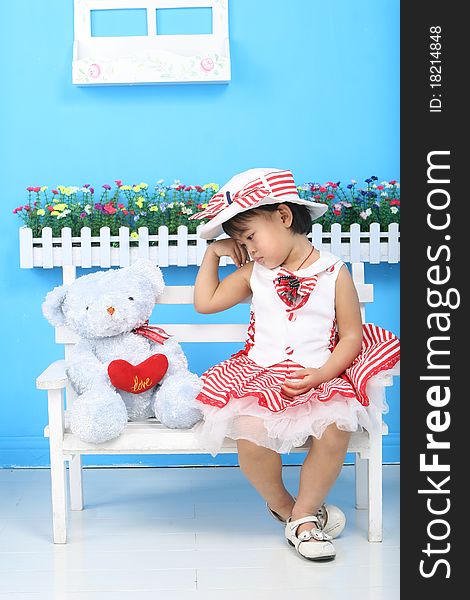 A girl and a toy bear sitting on the chair. A girl and a toy bear sitting on the chair.