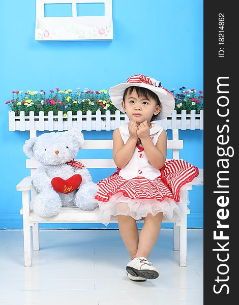 A girl and a toy bear sitting on the chair. A girl and a toy bear sitting on the chair.