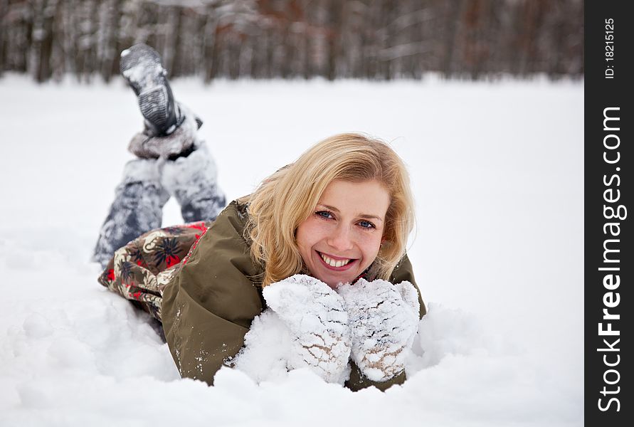 A beautiful woman is lying at the snow in the park. A beautiful woman is lying at the snow in the park