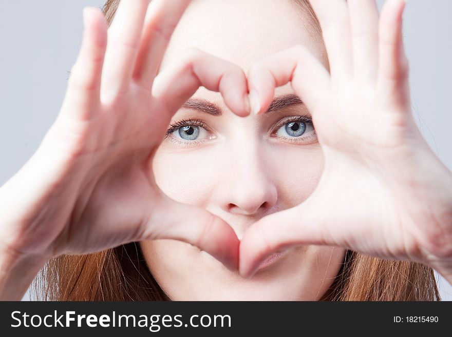 The beautiful girl shows heart from fingers