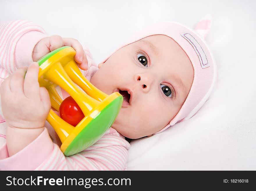 Closeup face of a beautiful newborn girl with rattle