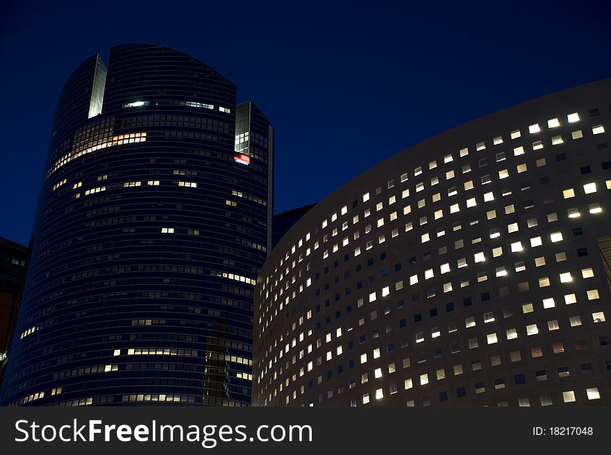 Skyline of modern skyscrapers with illuminated windows and dark sky during the night