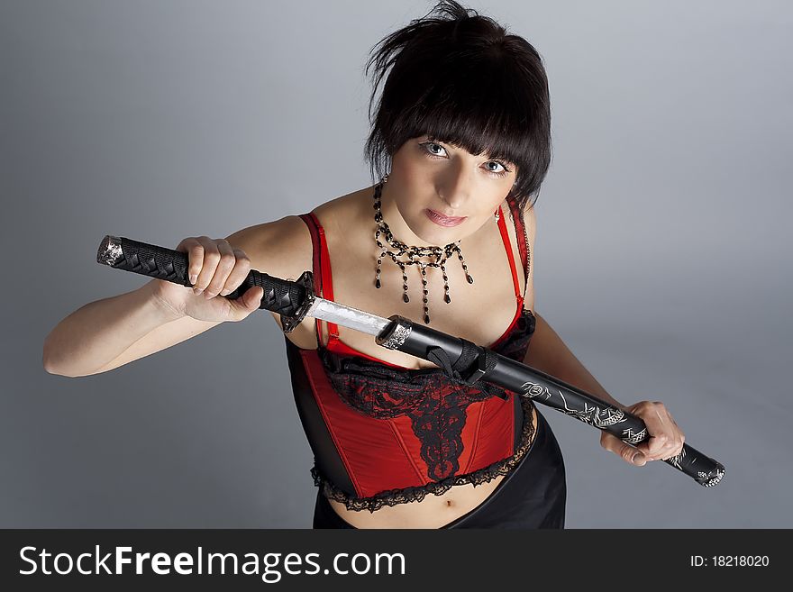 Woman in the studio with samurai sword on grey background