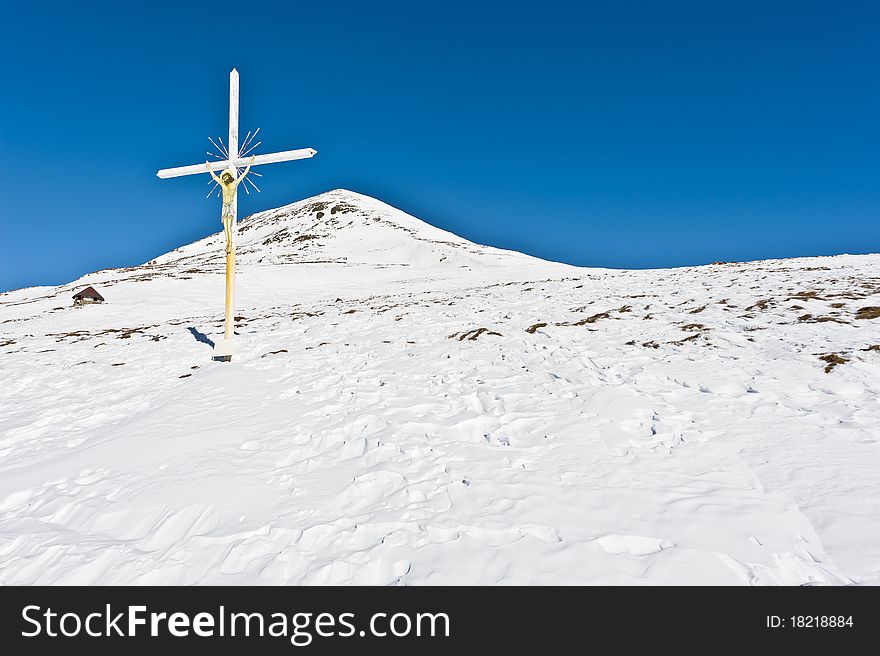 Christian cross with Jesus crucified in mountain landscape