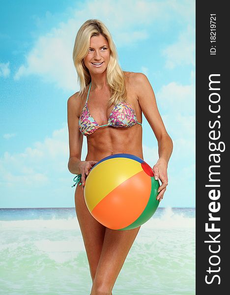 Beautiful blond woman with beach ball standing in front at the ocean. Beautiful blond woman with beach ball standing in front at the ocean