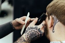 Male Haircut With Electric Razor. Tattooed Barber Makes Haircut For Client At The Barber Shop By Using Hairclipper. Man Royalty Free Stock Image