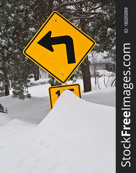 After a heavy snow storm a traffic sign is partially covered by snow. After a heavy snow storm a traffic sign is partially covered by snow.