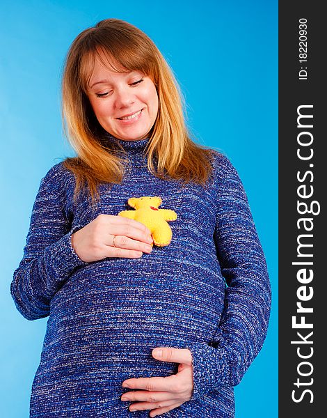 Beautiful pregnant woman with plush bear in her hand