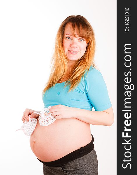 Beautiful pregnant woman with baby's bootees on white background
