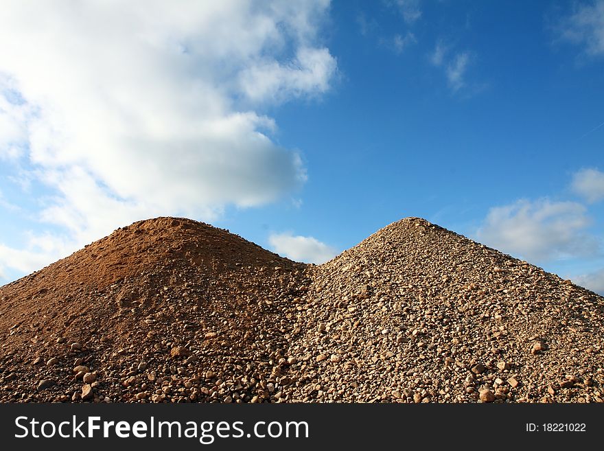 Two hills of stones with the blue and white sky in the background