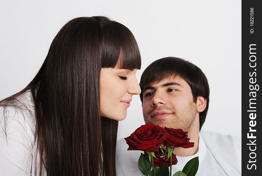 Pretty woman smelling roses, her boyfriend behind