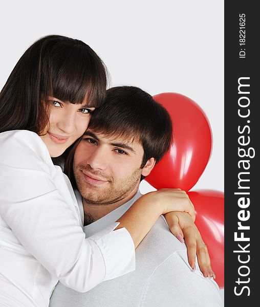 Young happy love couple, red balloons behind