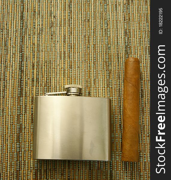 Cuban cigar and steel hip-flask. Close-up. Cuban cigar and steel hip-flask. Close-up