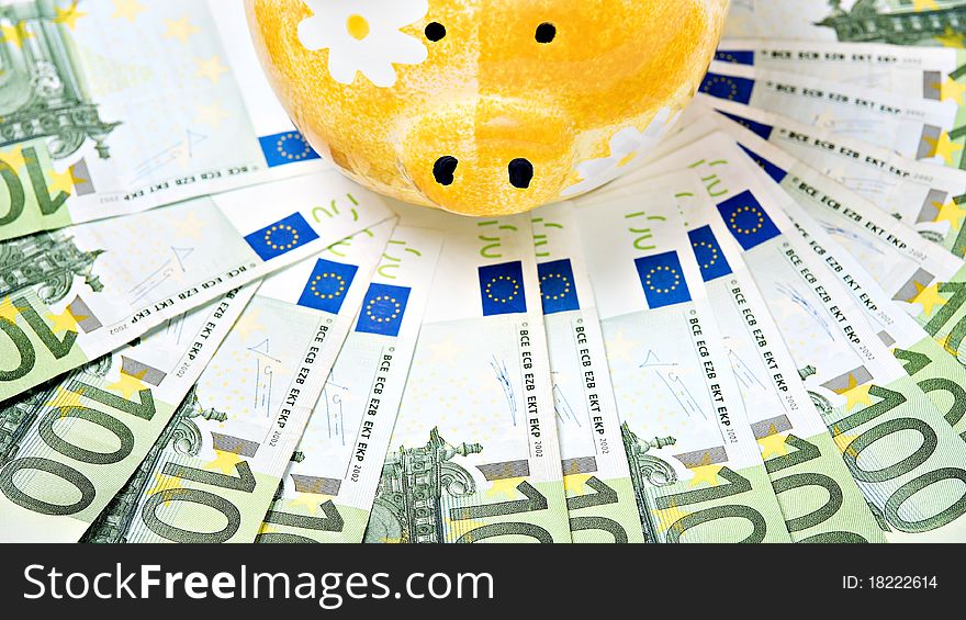 Yellow ceramic piggy bank on a pile of European banknotes. Yellow ceramic piggy bank on a pile of European banknotes