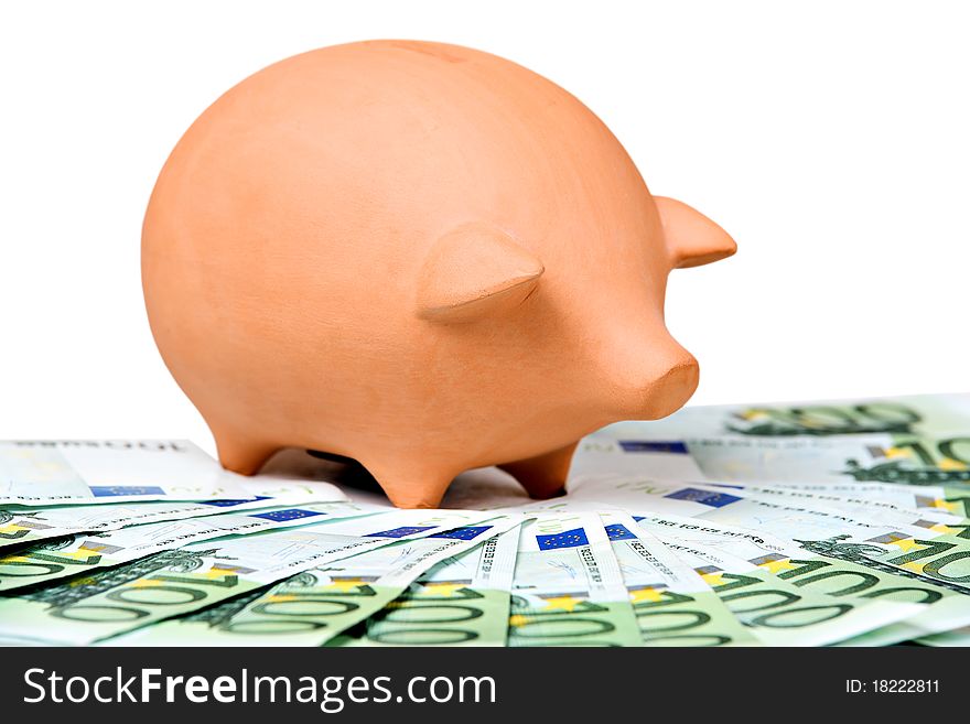 Clay piggy bank on a pile of European banknotes