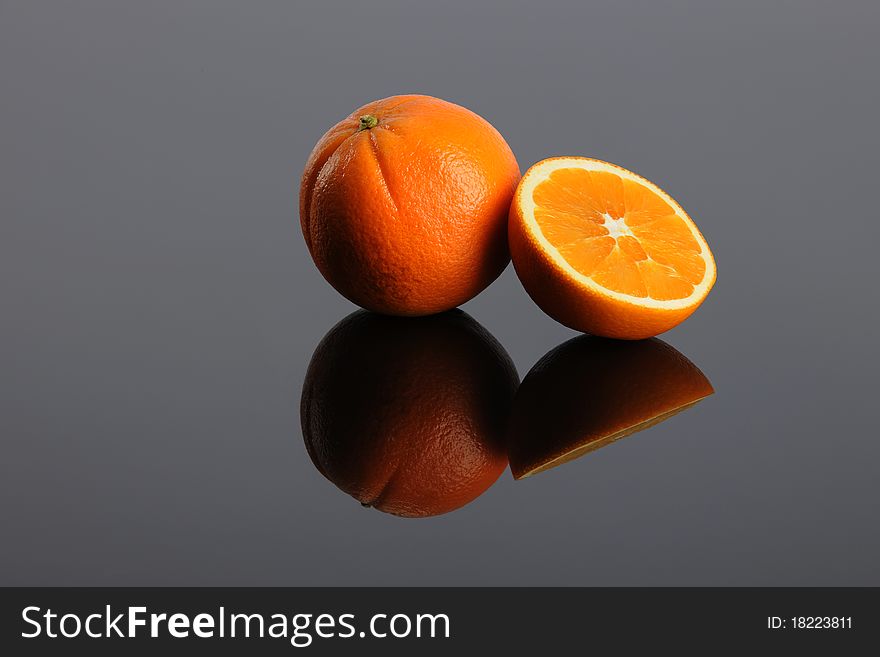 Oranges sitting on a shinny surface with reflection