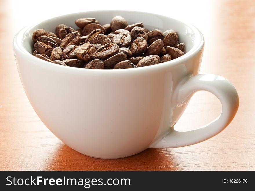Brown roasted coffee beans in a white cup