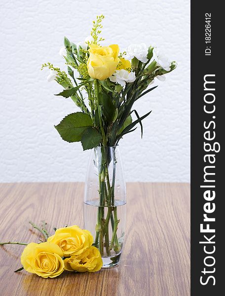 A vase of yellow roses sitting on a table. A vase of yellow roses sitting on a table