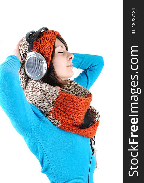 Happy beautiful girl wearing a hat and scarf listening to the music isolated against white background