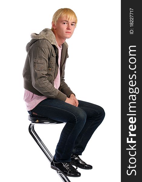 Young man in jacket with fur sits on stool