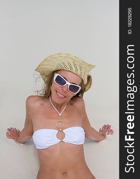 A young woman lies on sand at tropical beach