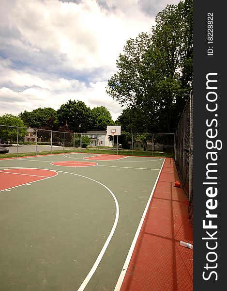 A well-used suburban basketball court, fenced in