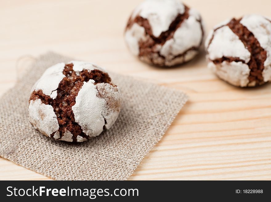 One chocolate crinkle on a piece of linen and two aside. One chocolate crinkle on a piece of linen and two aside.