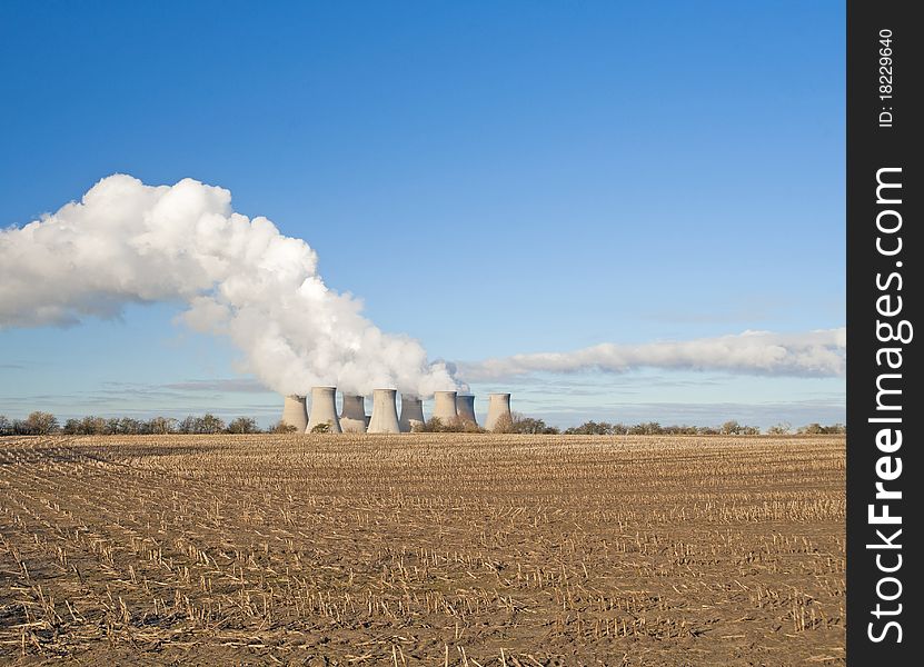 Cooling towers at a power station in the countryside giving off pollution. Cooling towers at a power station in the countryside giving off pollution