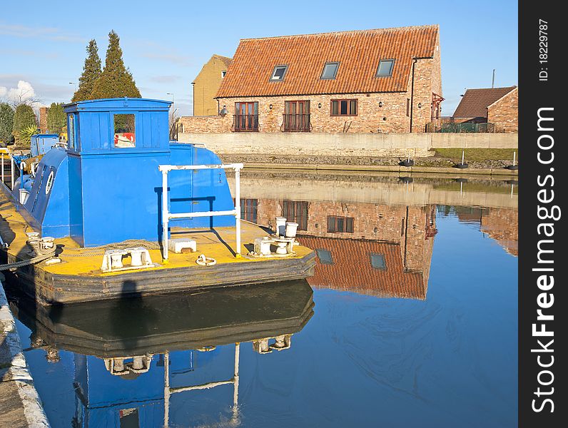 Houses in the countryside next to a small river with reflection and river boat. Houses in the countryside next to a small river with reflection and river boat