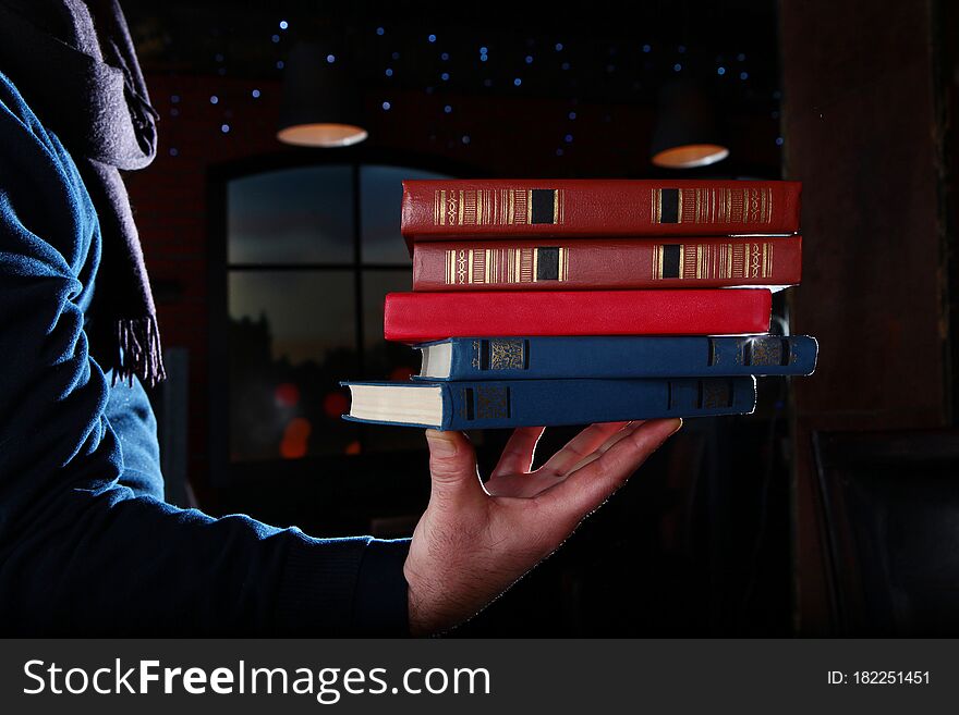 Books In A Man`s Hand. Unrecognizable Photo. Different Volumes Of Books. Photo On A Black Background. Copy Of The Space