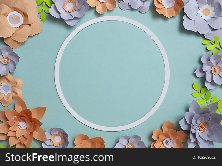 Flat lay of vintage round card frame, color paper flowers design on blue background. Top view, copy space, floral art,