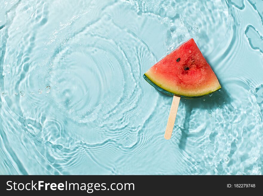 Wayermelon slice in water blue background, freshness, transparency, top view, copy space