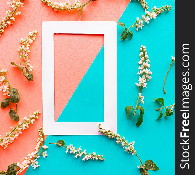 Mockup photo frame and blooming spring branches on geometric blue and pink background. Flat lay top view copy space. Springtime concept. Minimal concept