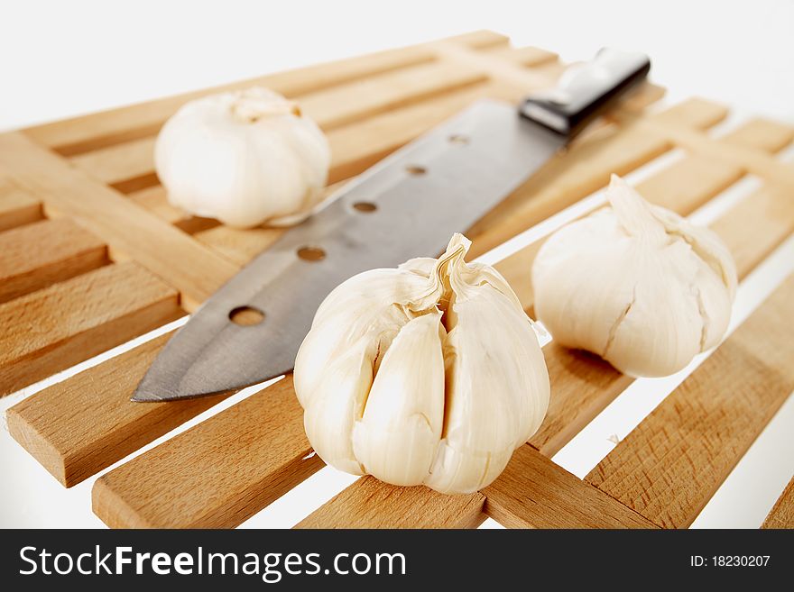 Garlic and knife on a wooden plate. Garlic and knife on a wooden plate