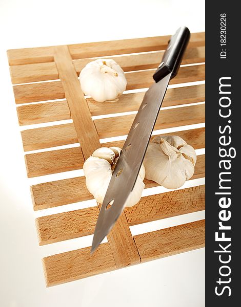 Garlic and knife on a wooden plate