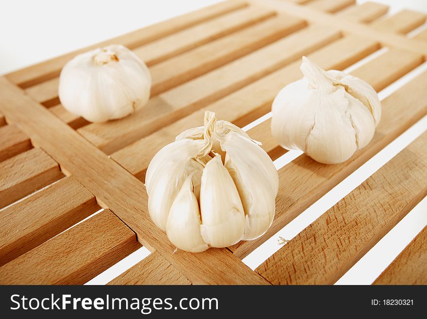 Garlic placed on a wooden plate with the white background