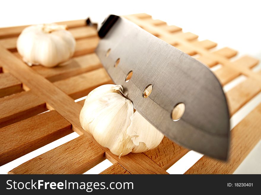 Knife cutting the garlic on a wooden plate. Knife cutting the garlic on a wooden plate